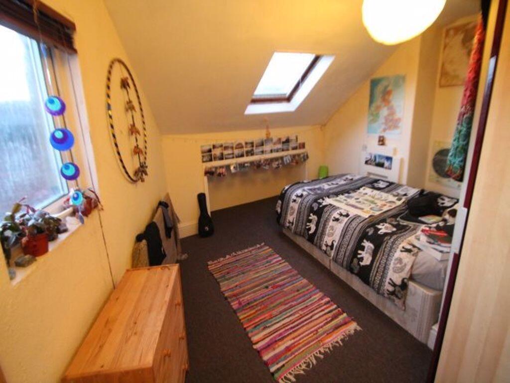 Cozy and bright single bedroom featuring a skyl...