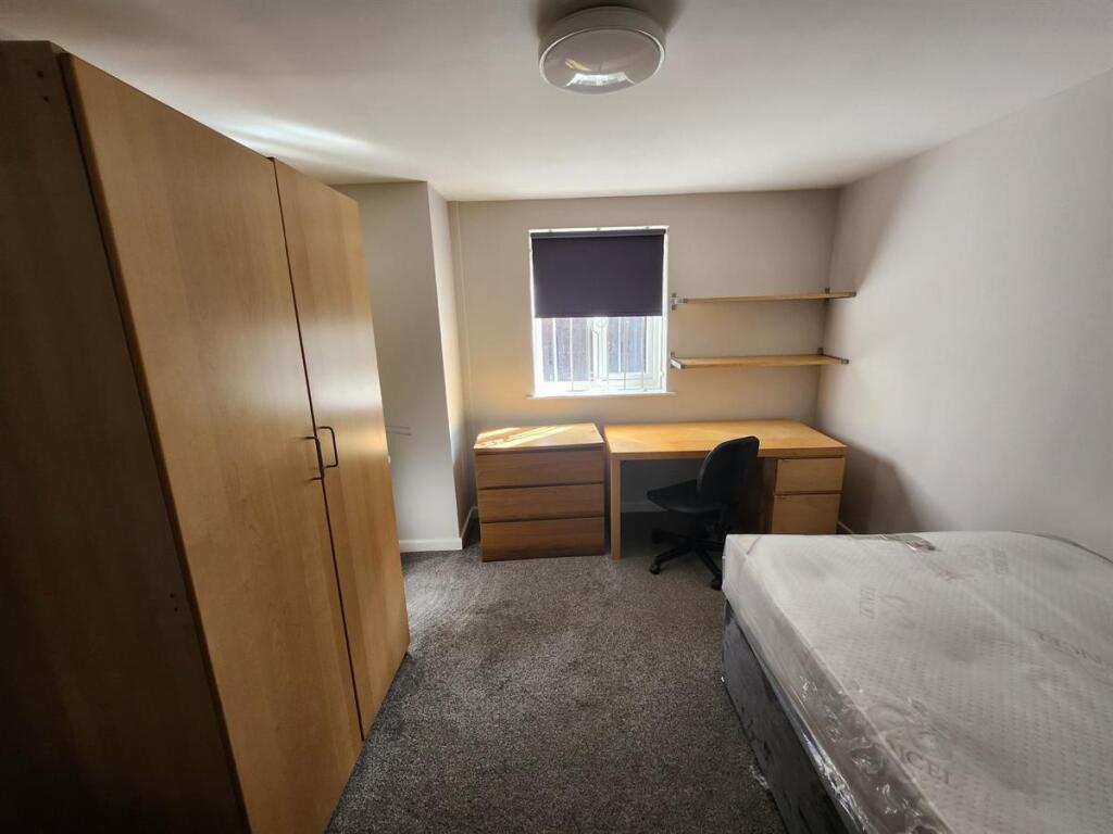 A neat and cozy student bedroom featuring a sin...