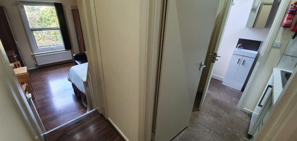 A bright single bedroom featuring wooden floori...