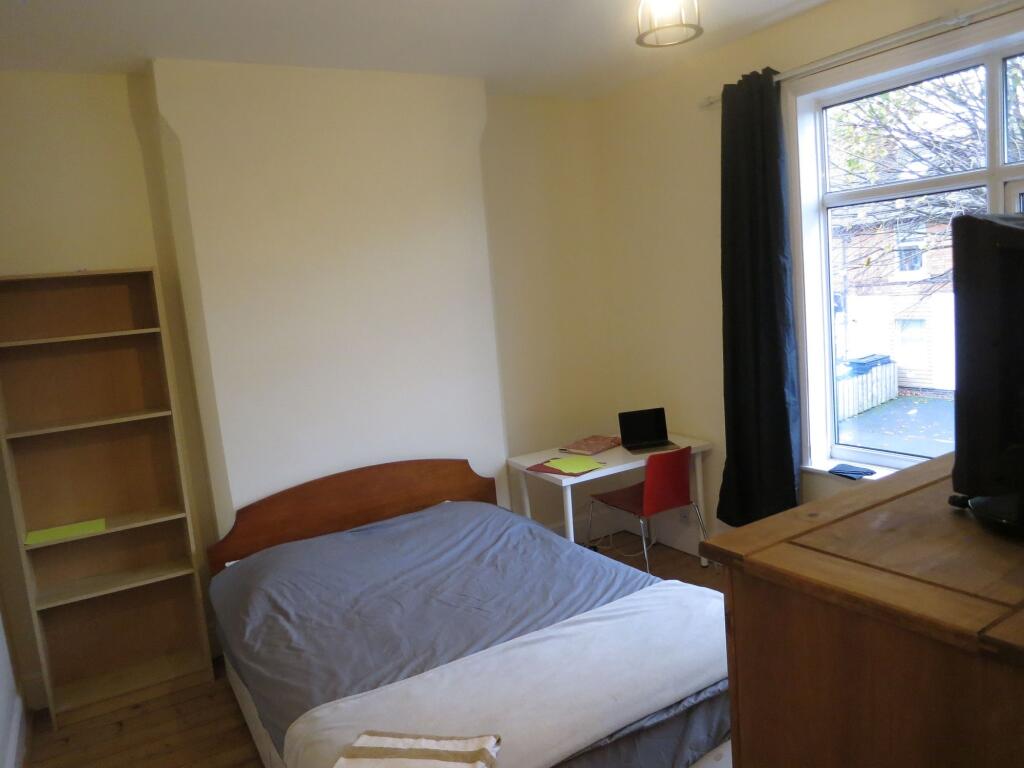 A tidy and well-lit bedroom featuring a simple ...