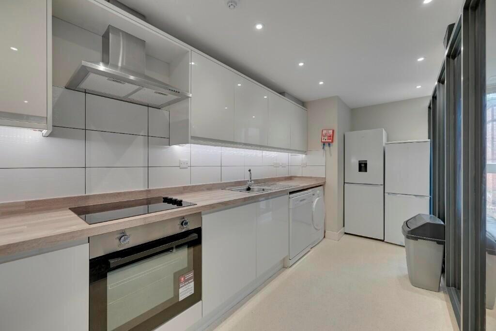 A modern kitchen featuring sleek white cabinetr...