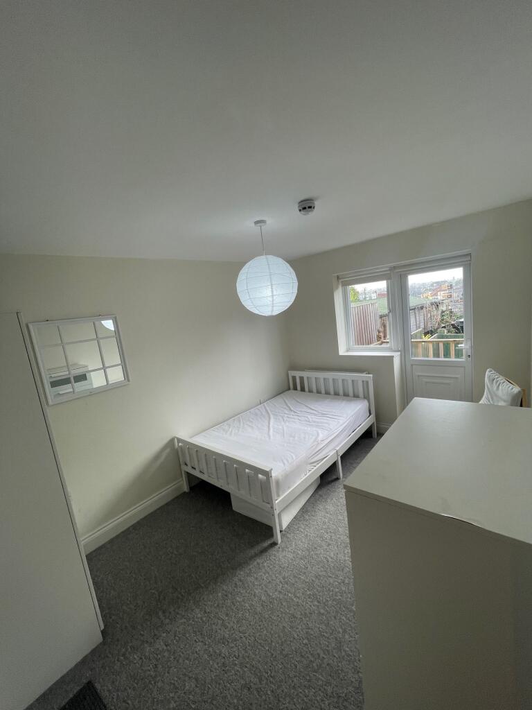 A tidy single bedroom featuring a white bed fra...