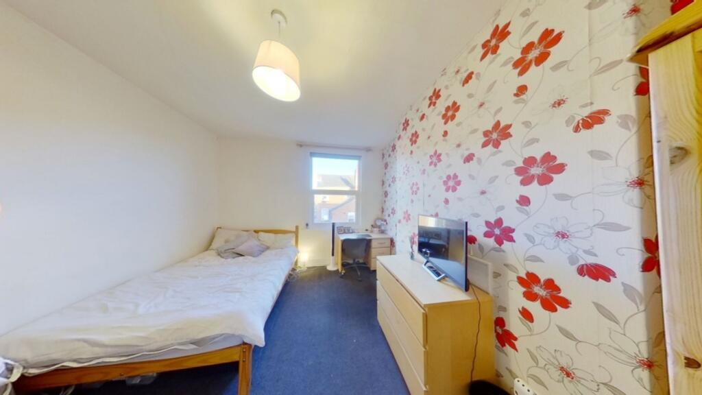 A bright and cozy single bedroom featuring flor...
