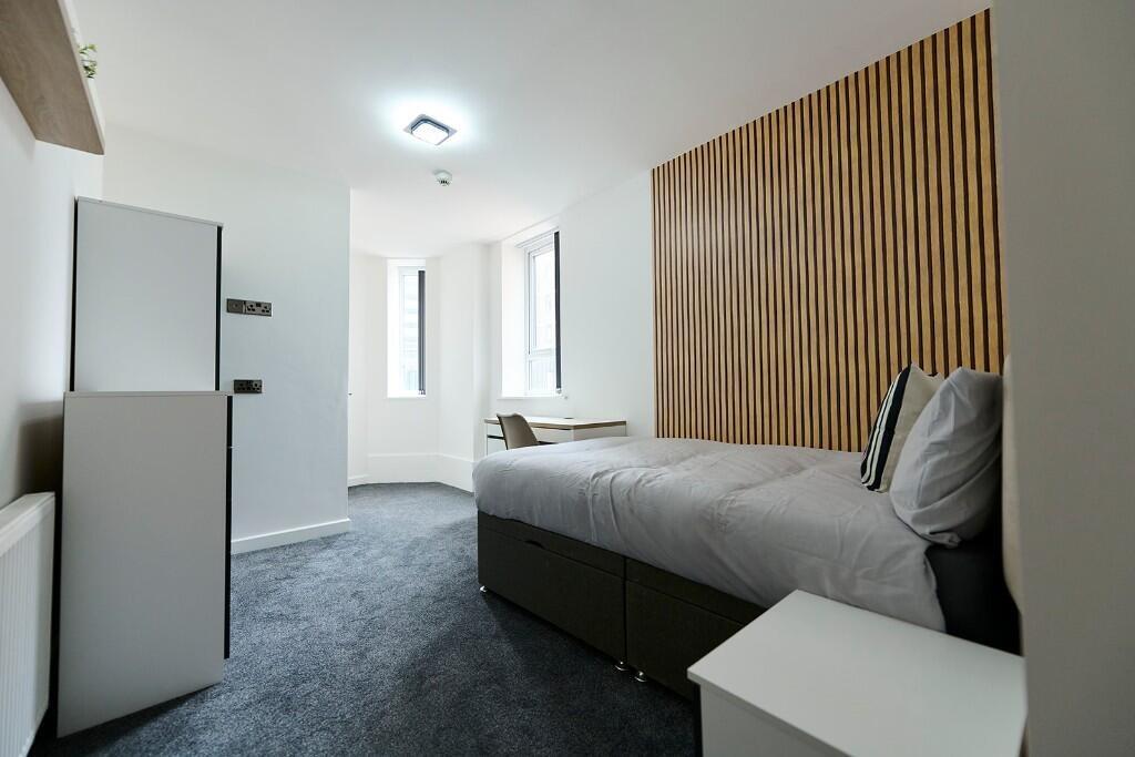 A clean, modern single bedroom featuring a comf...