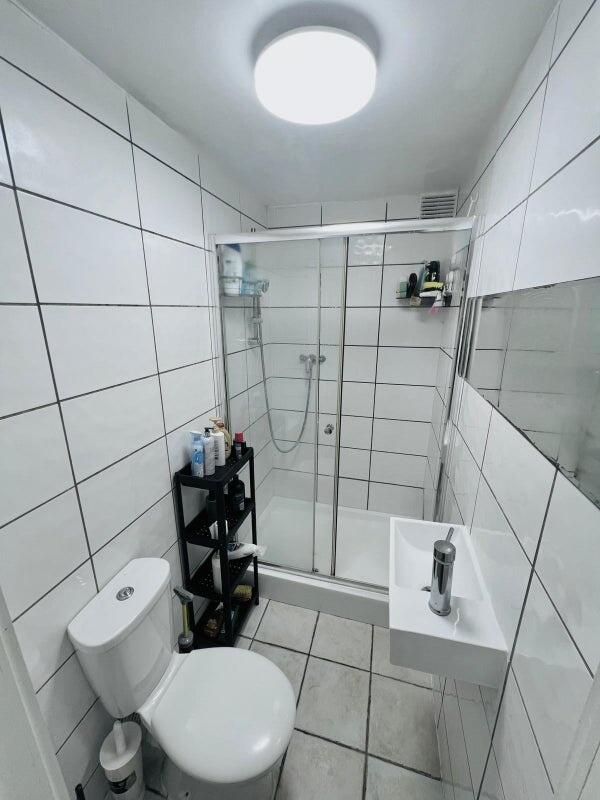 A modern bathroom featuring large white tiles, ...