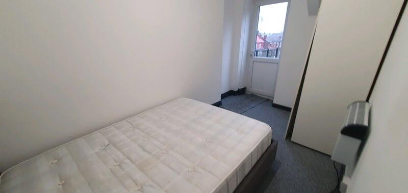 A small, basic room with a single bed and a win...