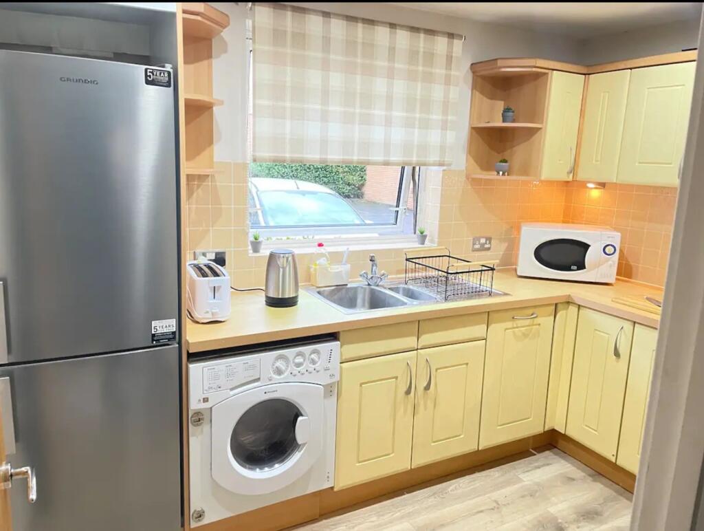 A bright and tidy kitchenette equipped with mod...