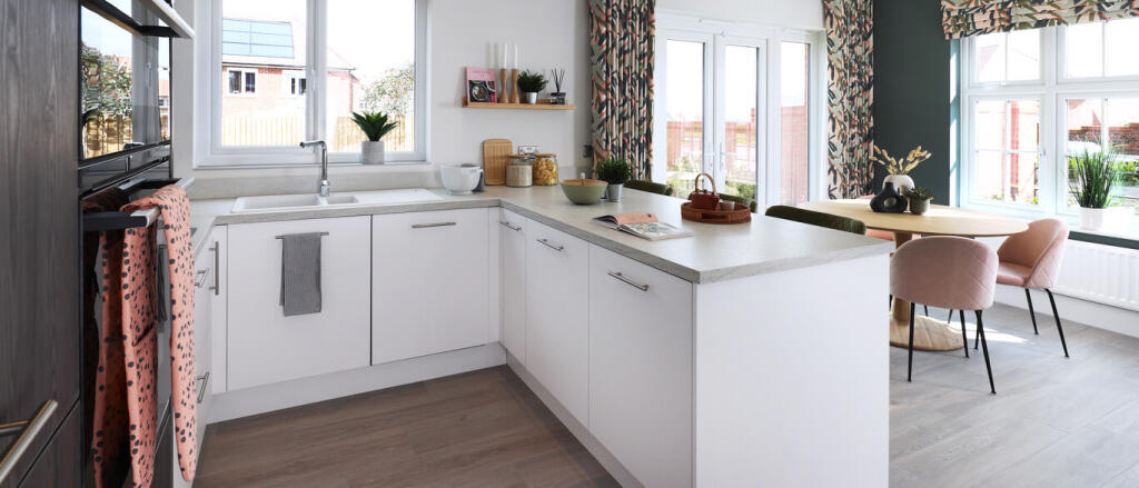 Modern kitchen with white cabinets, a central island, large windows, and a dining area with pink and