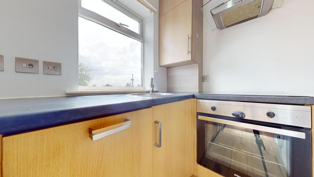 A modest kitchen with wooden cabinets and a bla...