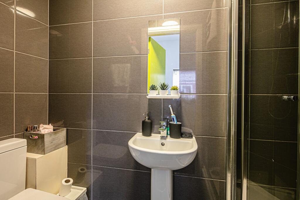 Modern tiled bathroom with a pedestal sink, wal...