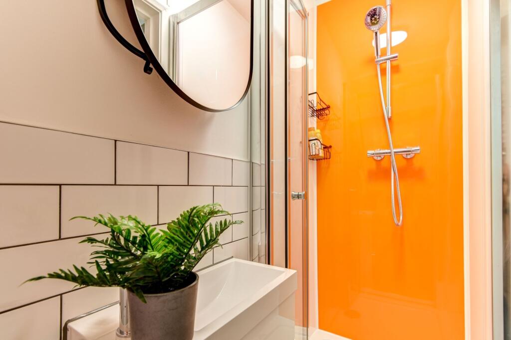 This modern bathroom features a bright orange a...