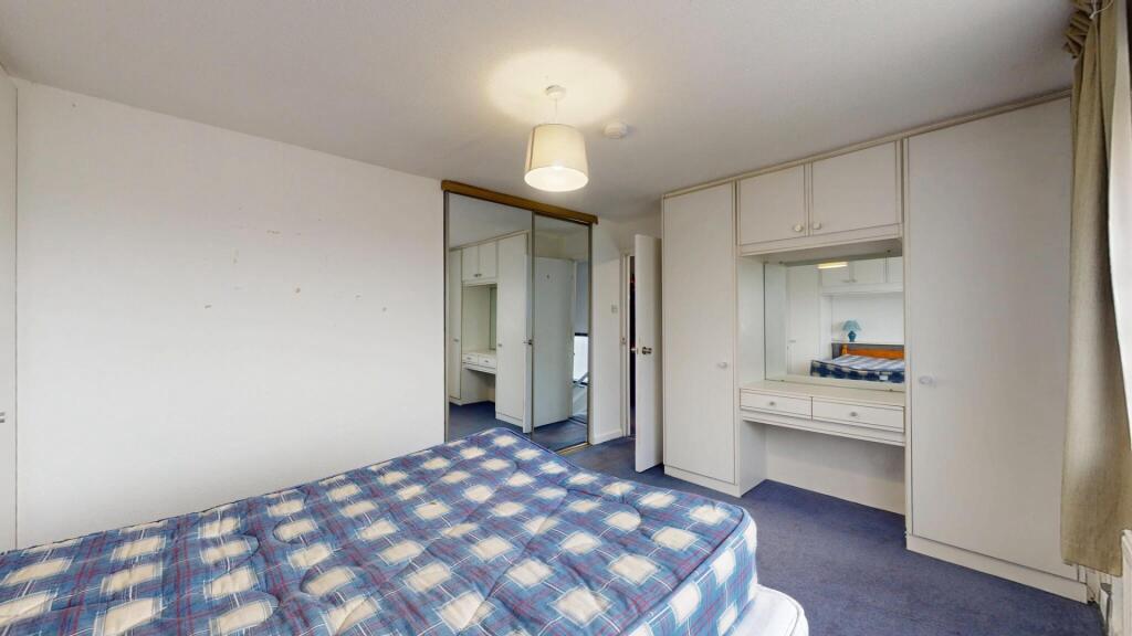 A clean, well-lit bedroom with a comfortable be...