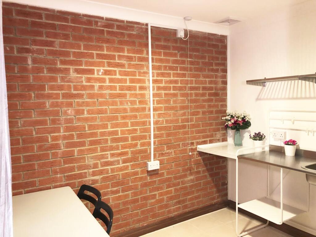 Bright, modern kitchenette with exposed brick f...