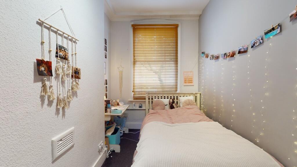 Cozy single bedroom with a neatly made bed, sof...