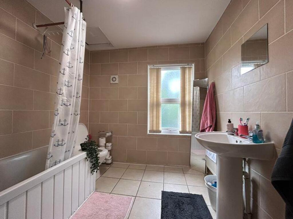 A spacious and tidy bathroom featuring a bath a...