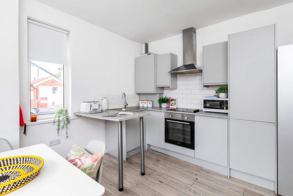 A modern and bright kitchen featuring white cab...