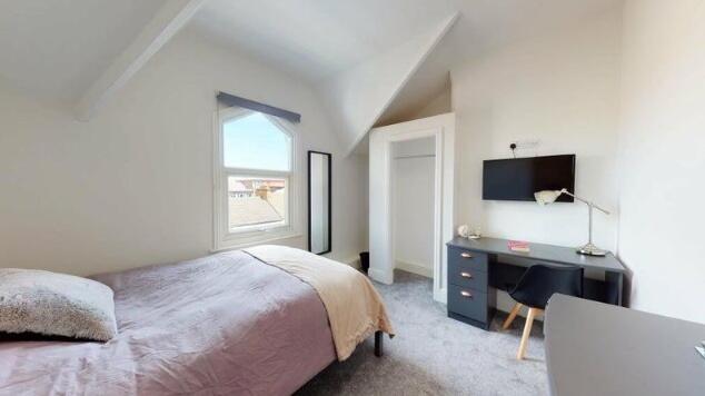 A bright double bedroom featuring a cozy bed wi...