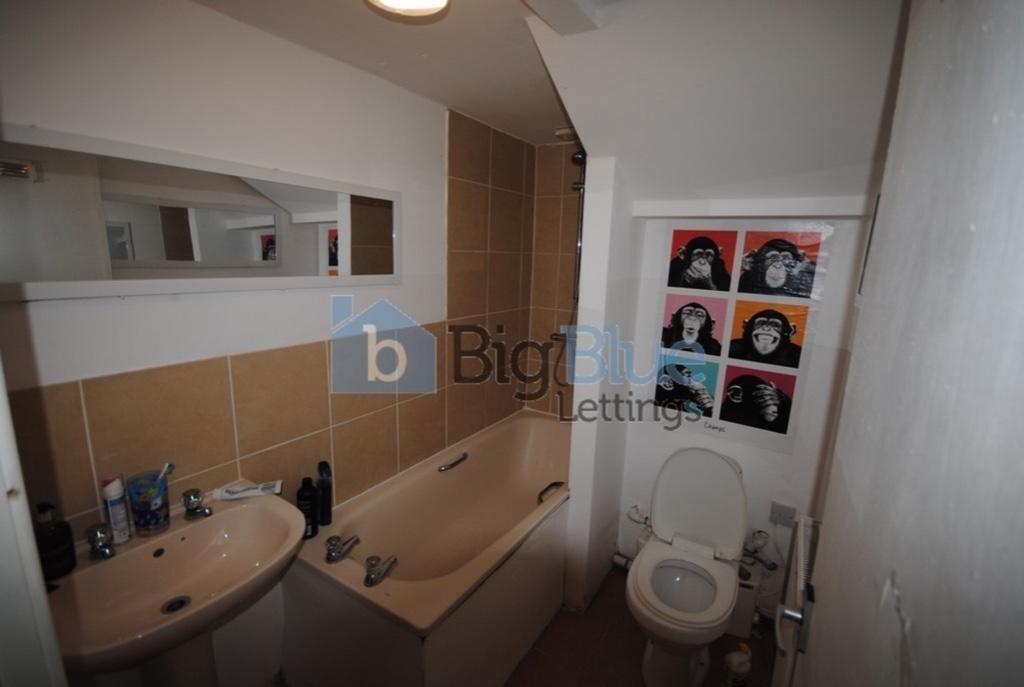 A compact bathroom featuring a bathtub, sink, a...