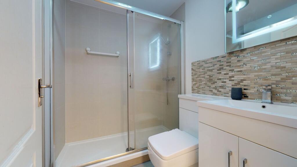 Modern bathroom featuring a spacious shower enc...
