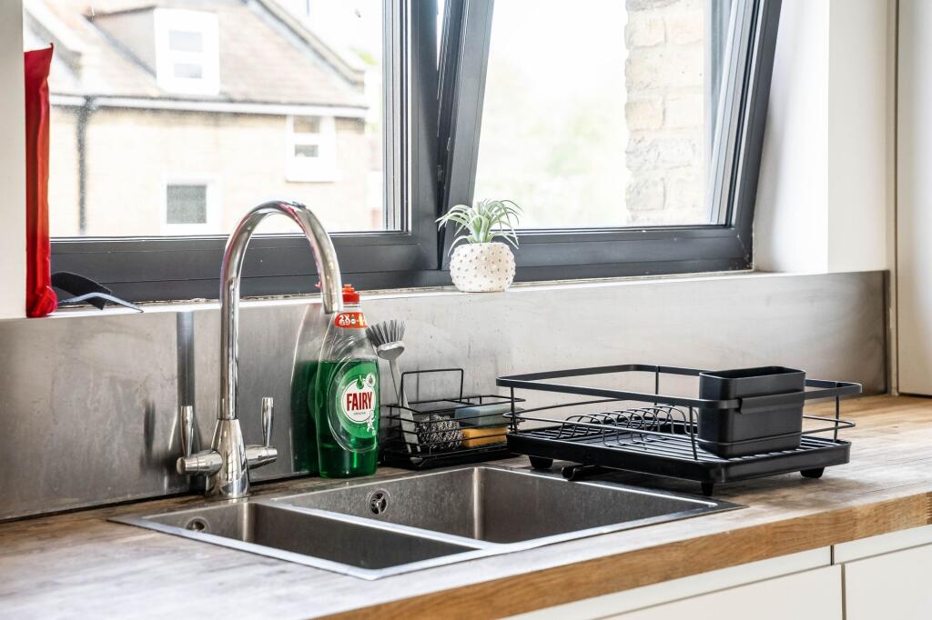 This modern kitchen features sleek countertops ...