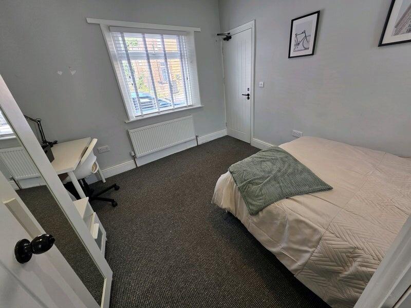 A neat and tidy single bedroom featuring a comf...
