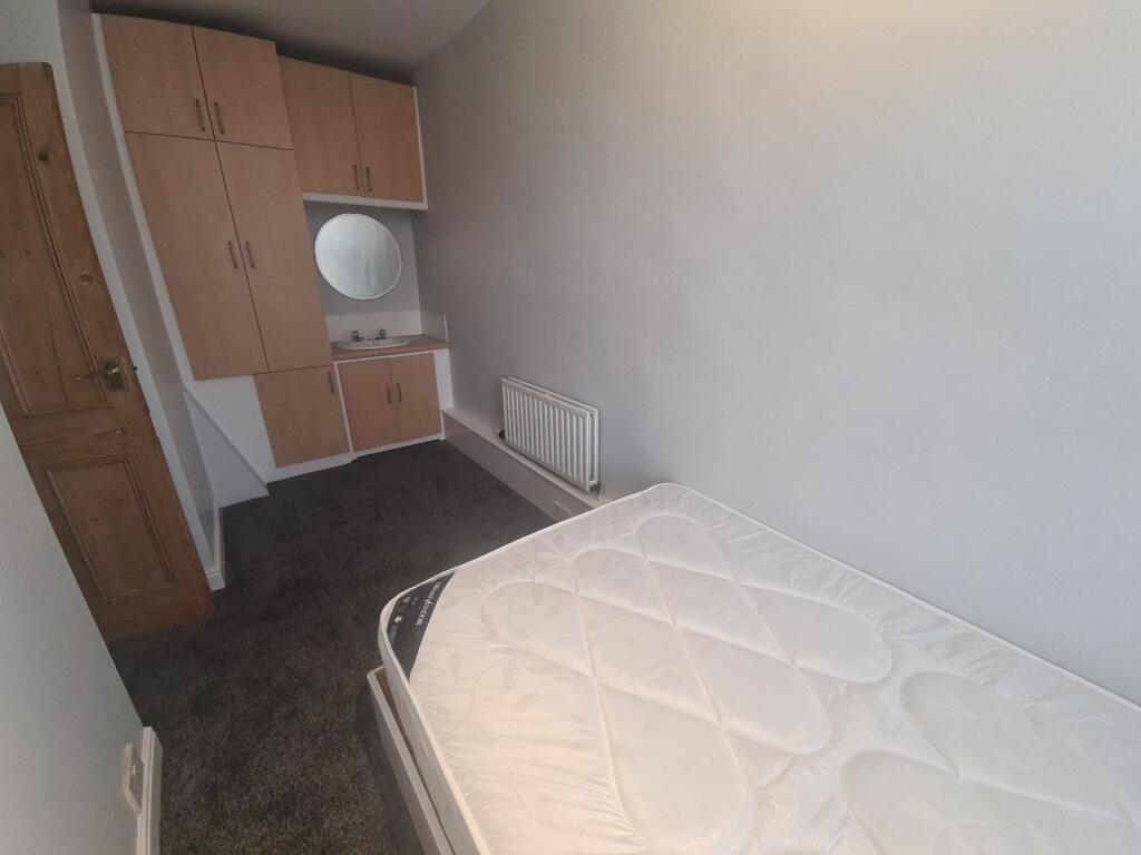 A compact single bedroom featuring a built-in w...