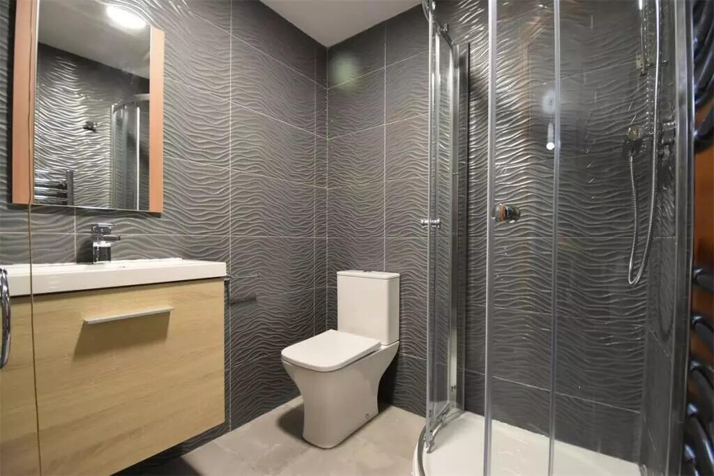 Modern bathroom featuring textured grey tiles, ...