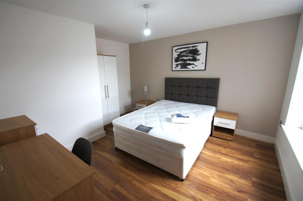 A spacious double bedroom with a comfortable be...