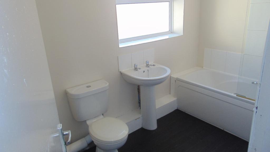Bright and clean bathroom suite featuring a whi...