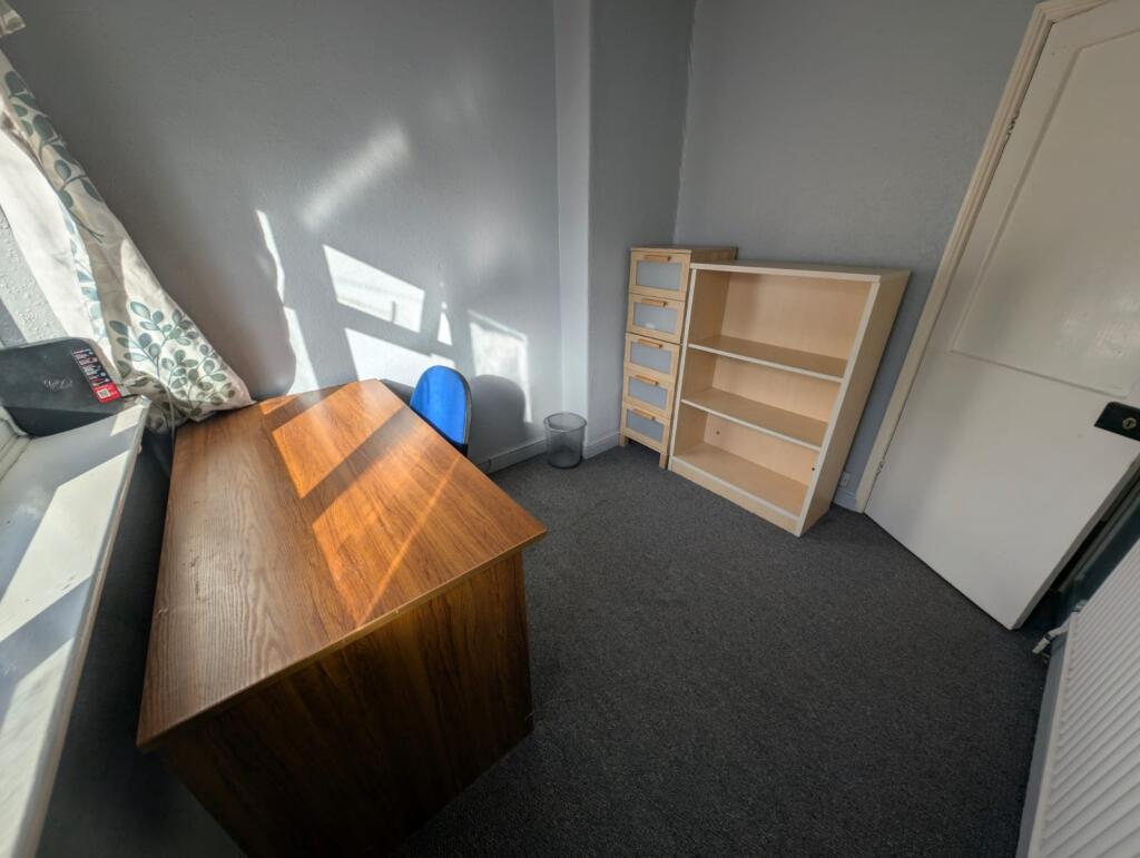 A compact room with a wooden desk bathed in nat...