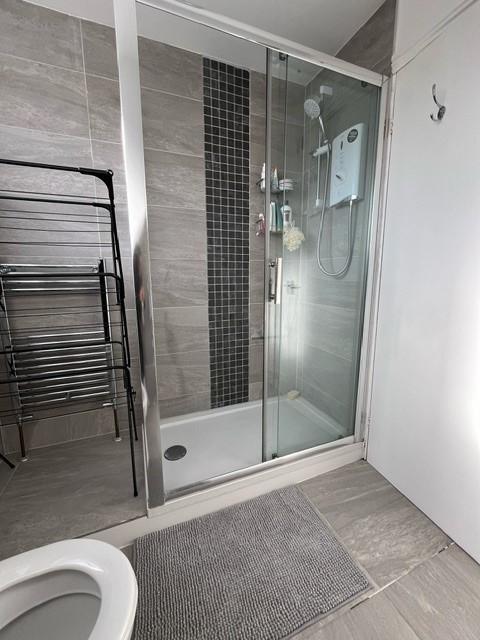 Modern tiled bathroom featuring a glass-enclose...