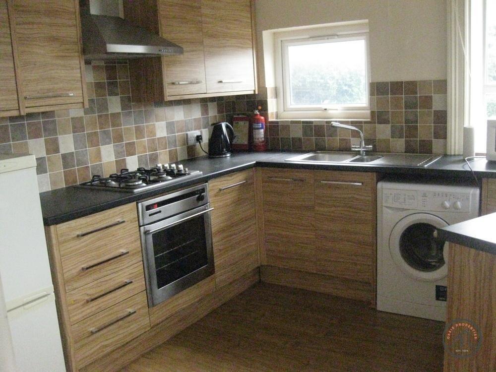 A modern kitchen with wooden cabinets, a gas st...