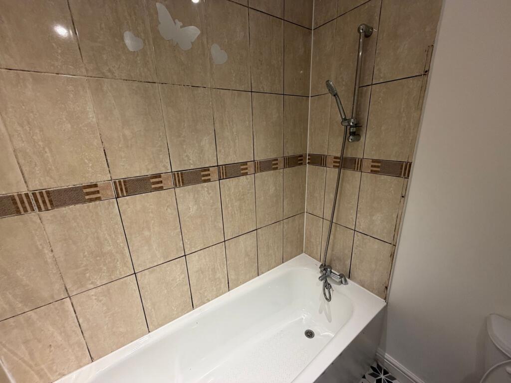 A clean bathroom featuring a beige tiled wall w...