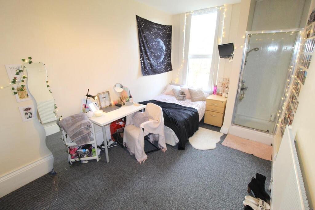 Bright furnished bedroom with a desk, mirror an...