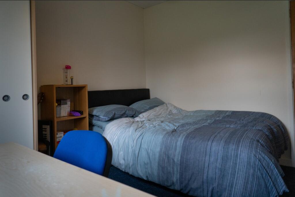 A cozy double bedroom with ample space for stud...