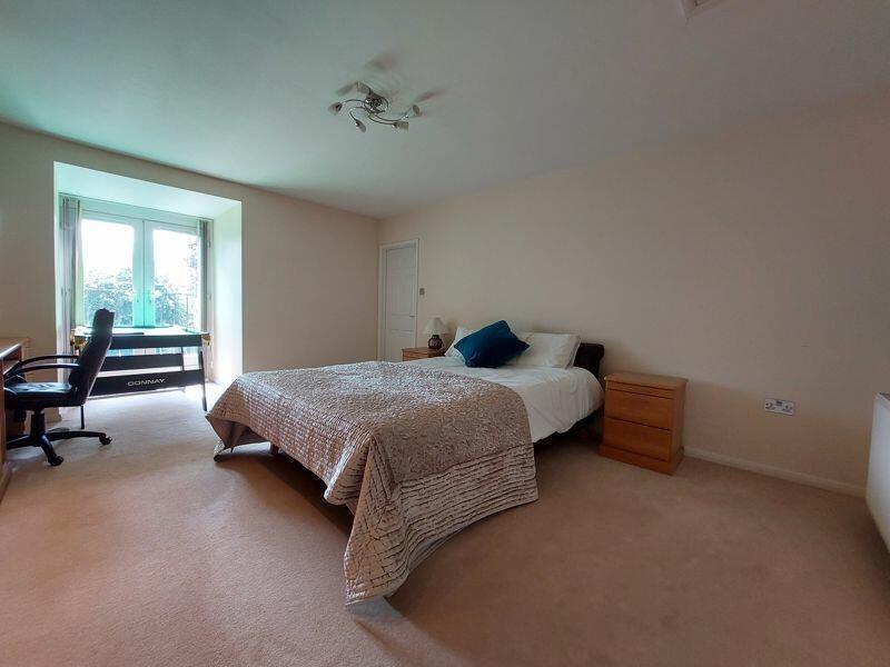 A spacious master bedroom featuring a comfortab...