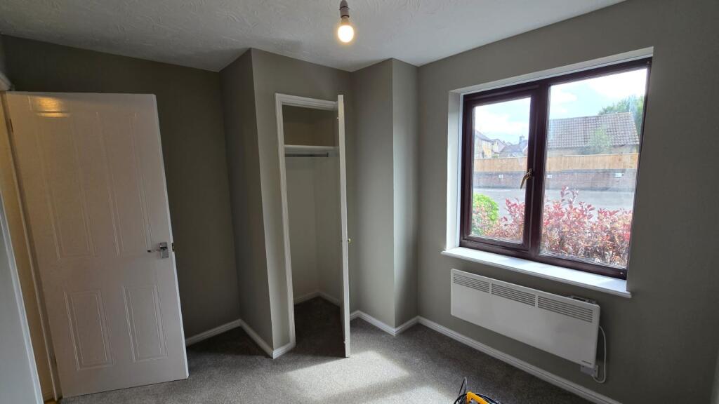 A bright and tidy bedroom featuring a large win...