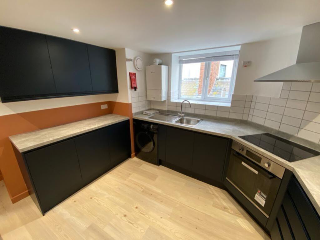 Modern kitchen featuring sleek black cabinetry,...