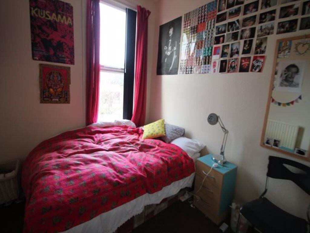 Cozy single bedroom featuring a bright window w...