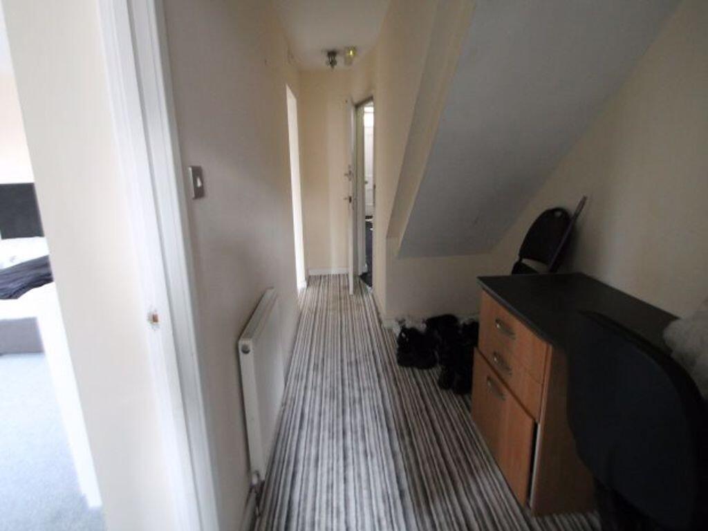 Bright, narrow hallway with striped runner carp...