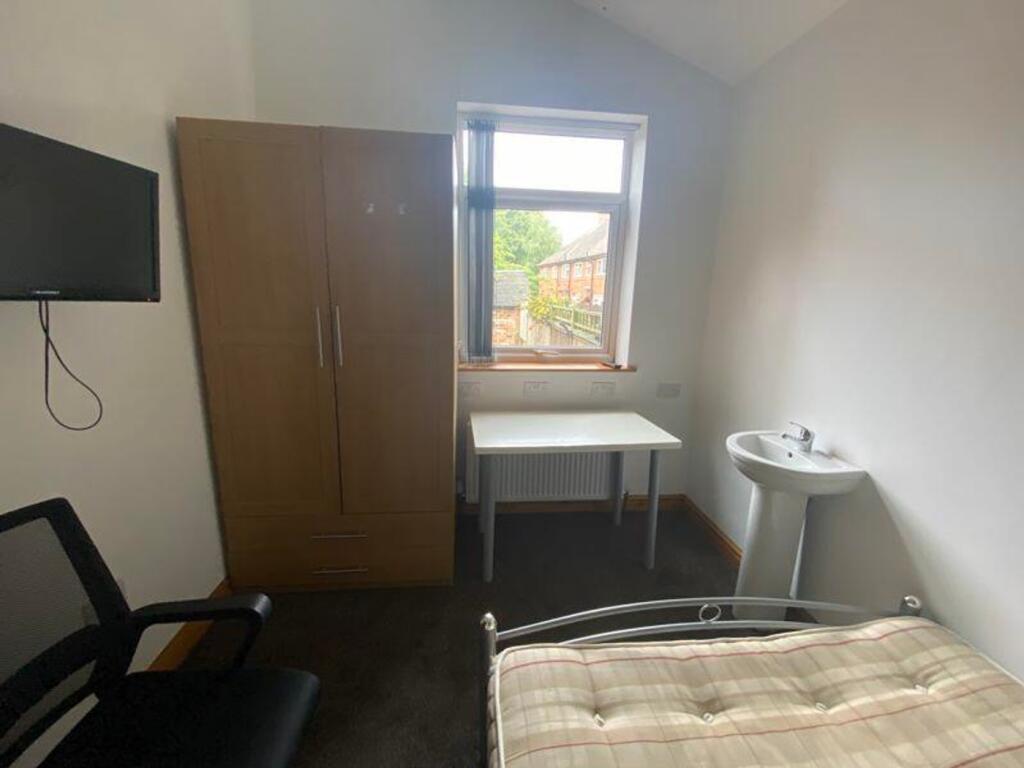 A bright and tidy double bedroom with a desk an...