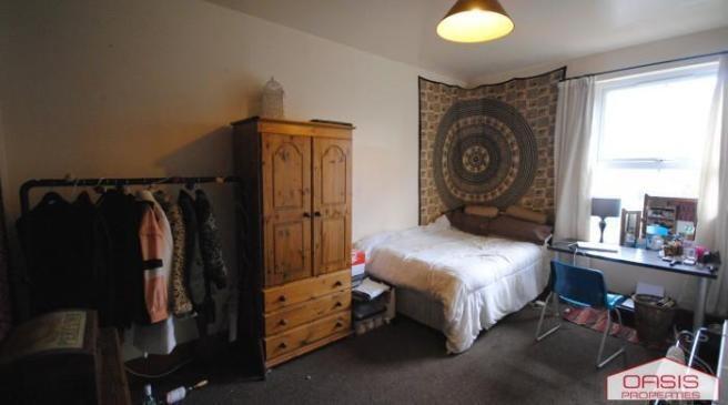A cozy bedroom featuring a neatly made bed, bri...
