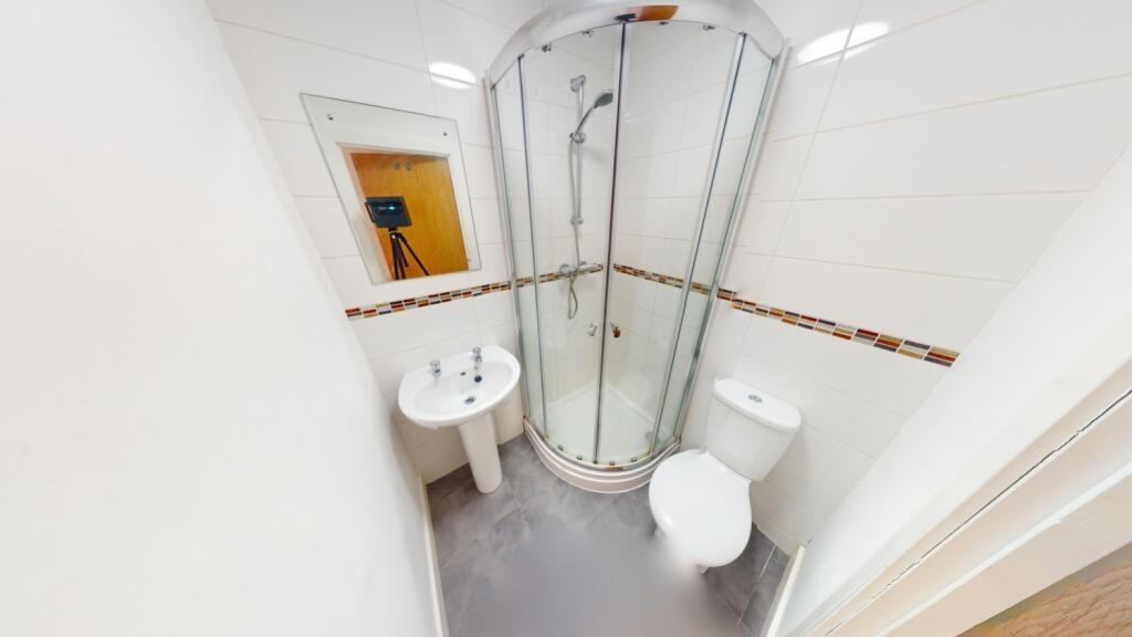 A compact, modern bathroom featuring a curved g...