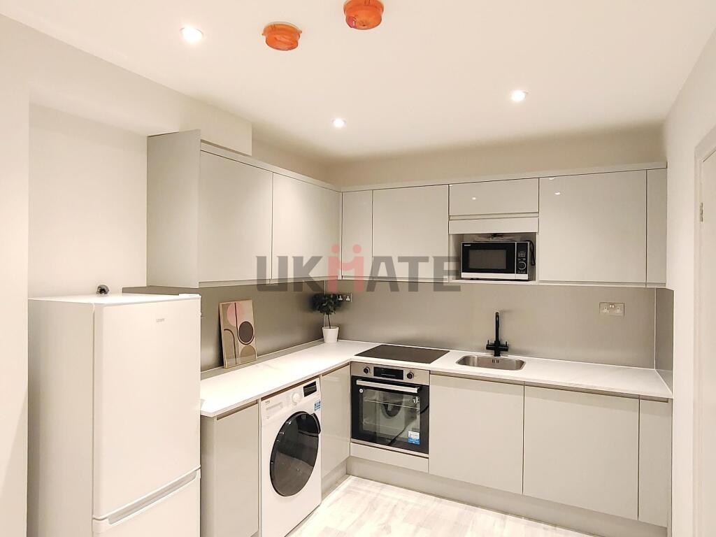 Modern and sleek kitchen with white cabinetry, ...