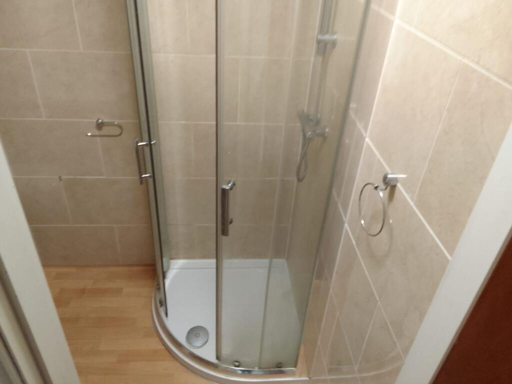 A modern bathroom featuring a curved glass show...