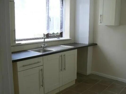 A bright and tidy kitchen with white cabinets, ...
