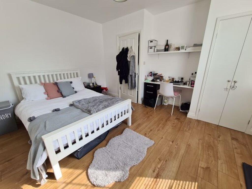 A bright and tidy bedroom featuring a cozy bed ...