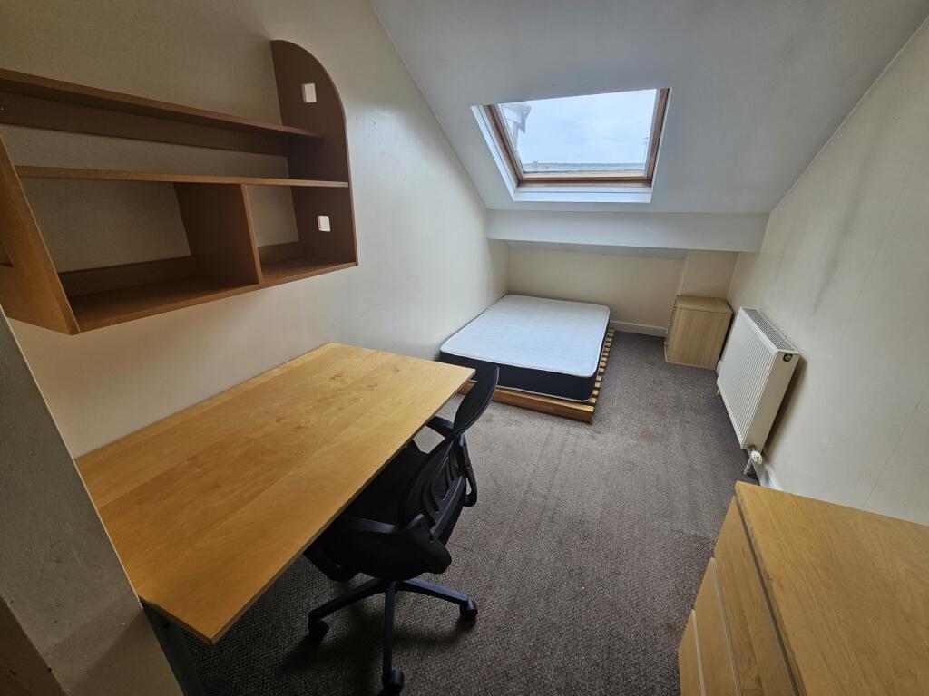 A compact, tidy single bedroom featuring a skyl...