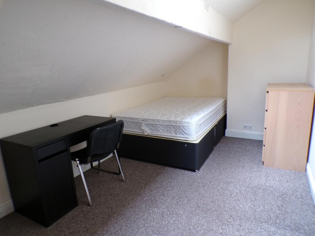 A spacious double bedroom featuring a desk and ...