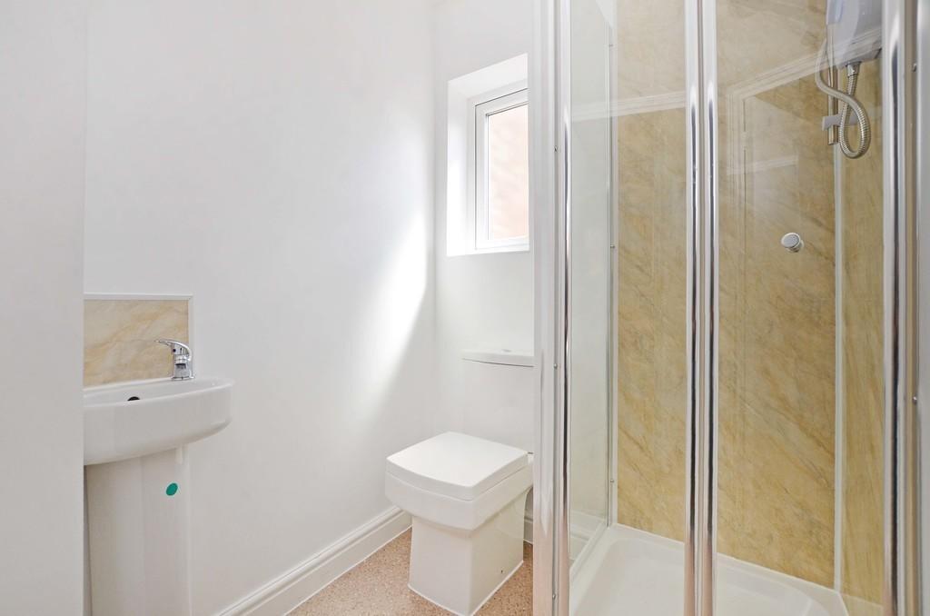 A bright, modern bathroom featuring a clear gla...